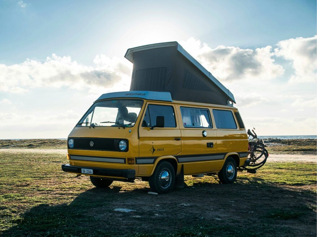 Yellow motorhome parked up in fields next to the sea - sunny day 