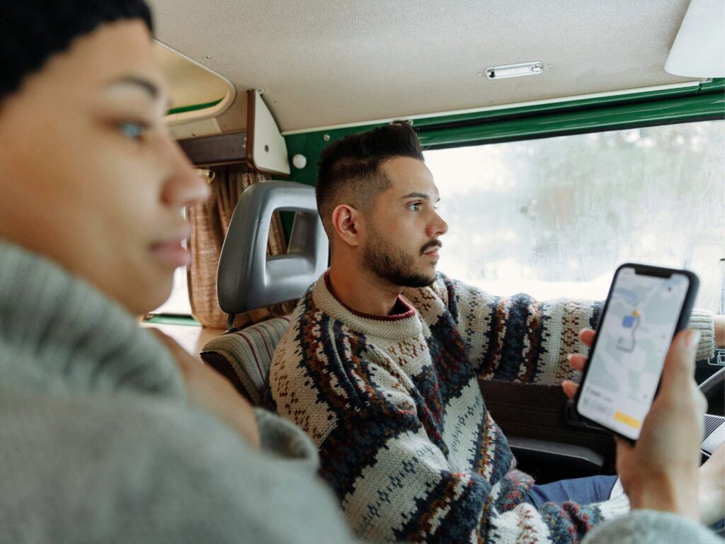 Young couple using map on smartphone while driving campervan 