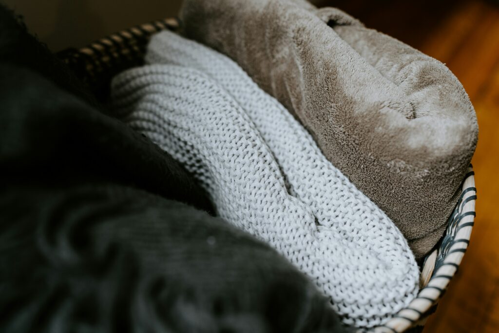 Close-up of three grey blankets folded and placed in a decorative blanket 